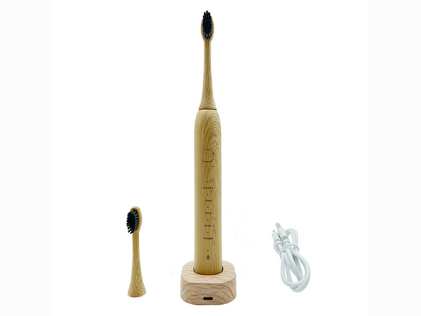 a bamboo electric toothbrush is standing upright on its bamboo charger with a electric charge and spare toothbrush head on either side